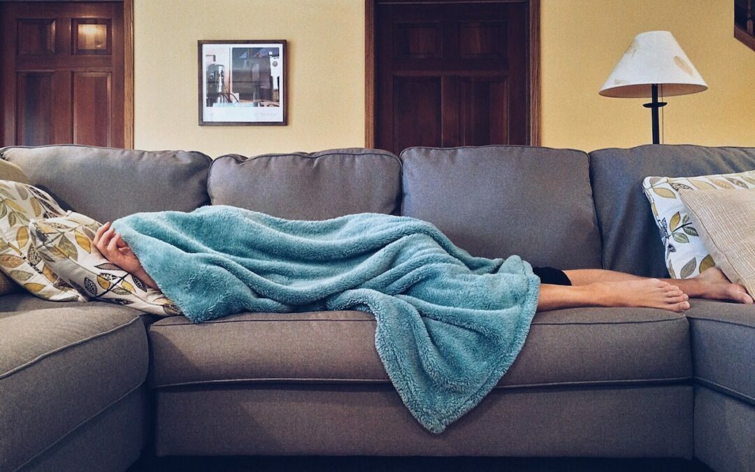 person lying on the couch under the blanket